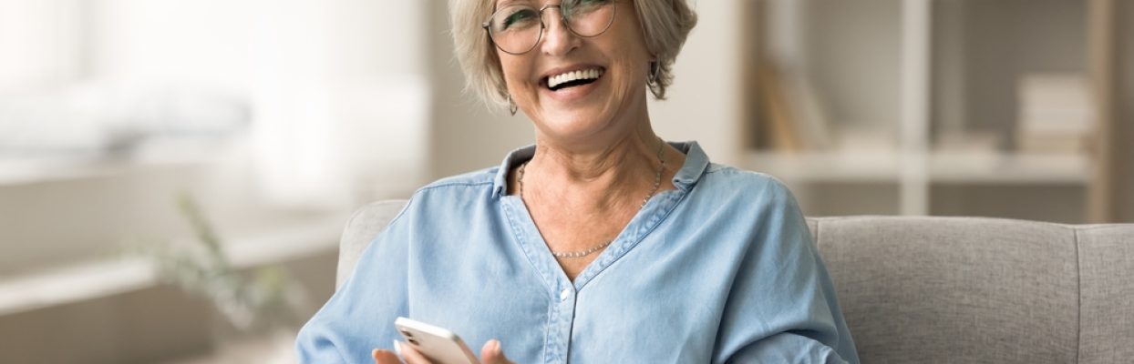 Cheerful,Pretty,Older,Retired,Woman,In,Stylish,Glasses,Holding,Smartphone