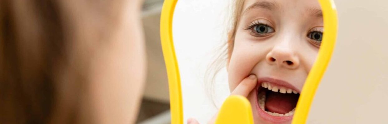 child checking in the mirror to see her cleaned teeth